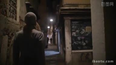 慢动作斯坦尼康拍摄的一个女人走在小巷与昏暗的灯光夜晚城市与破旧的垃圾建筑